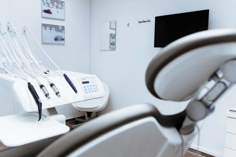 Clean dental treatment room with chair, instrument unit and wall-mounted screen