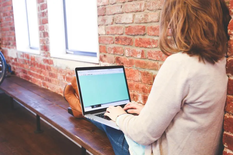 Practice owner working on a laptop at a window bench, screen not readable